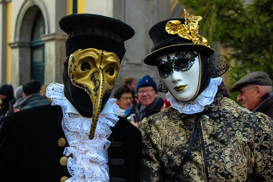 Venice Carnival masked figures in elaborate historical costumes on canal bridge